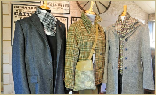 Three splendid woollen coats standing in the entrance lobby at Cotswold Woollen Weavers